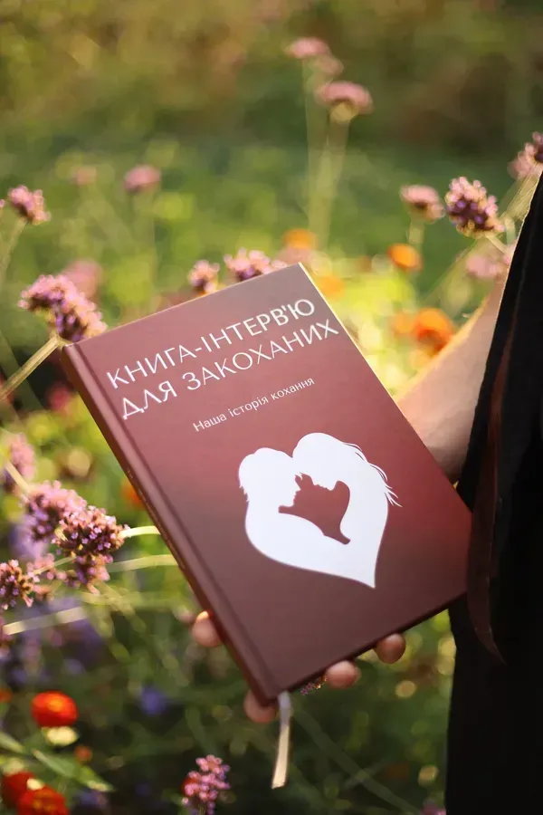 Книга-інтерв'ю для закоханих у руках серед квітів