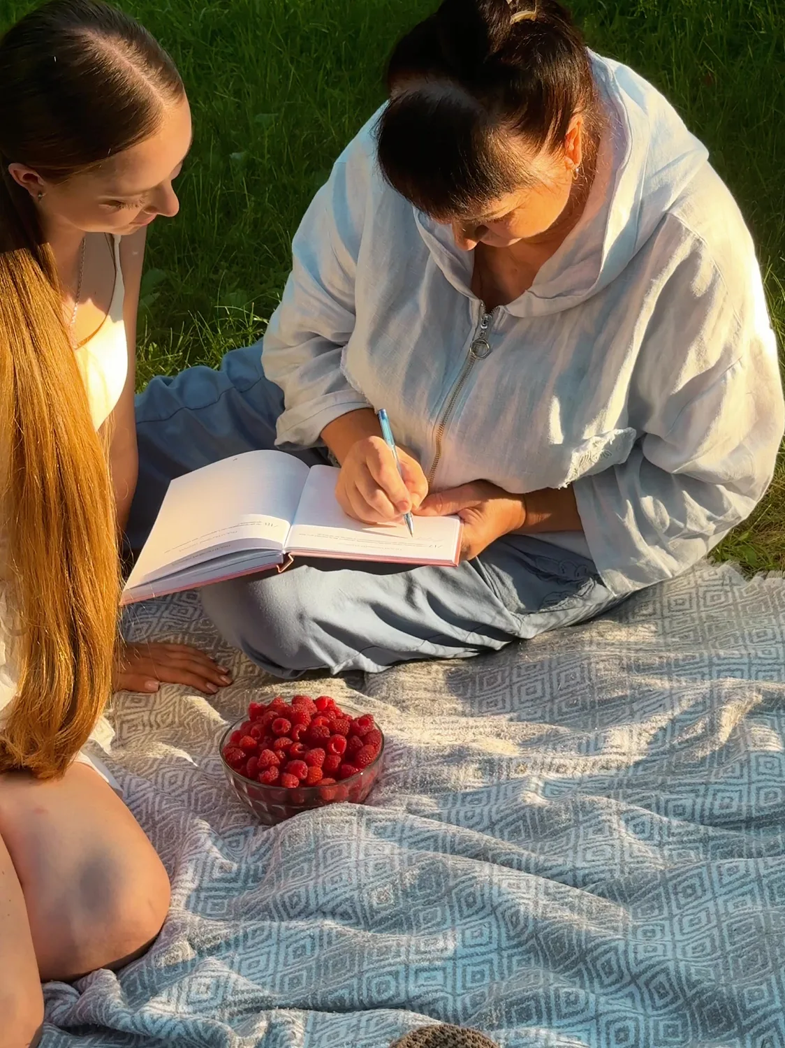 Онука й бабуся заповнюють книгу-інтерв'ю на пікніку
