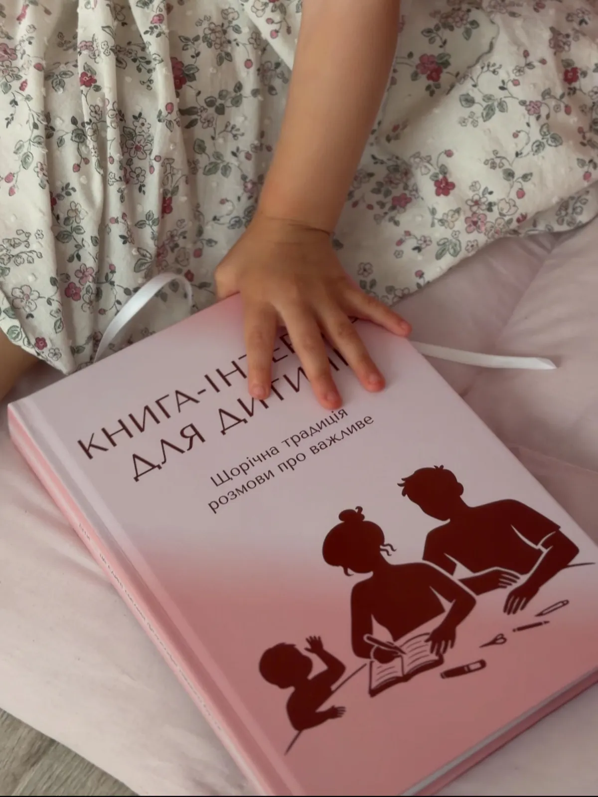 Детская рука на розовой книге-интервью
