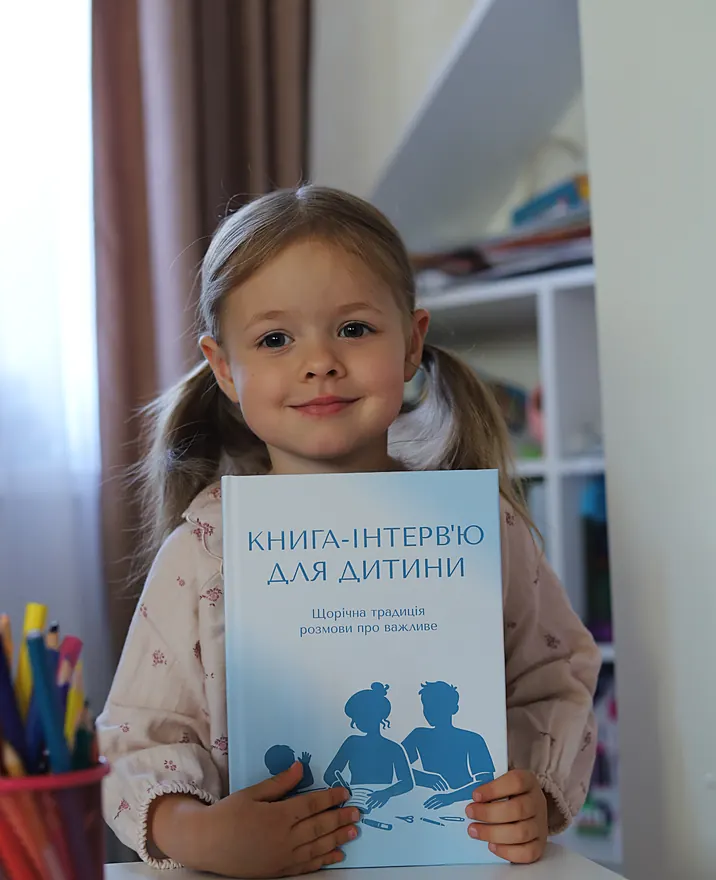 Дівчинка тримає книгу-інтерв'ю для дитини